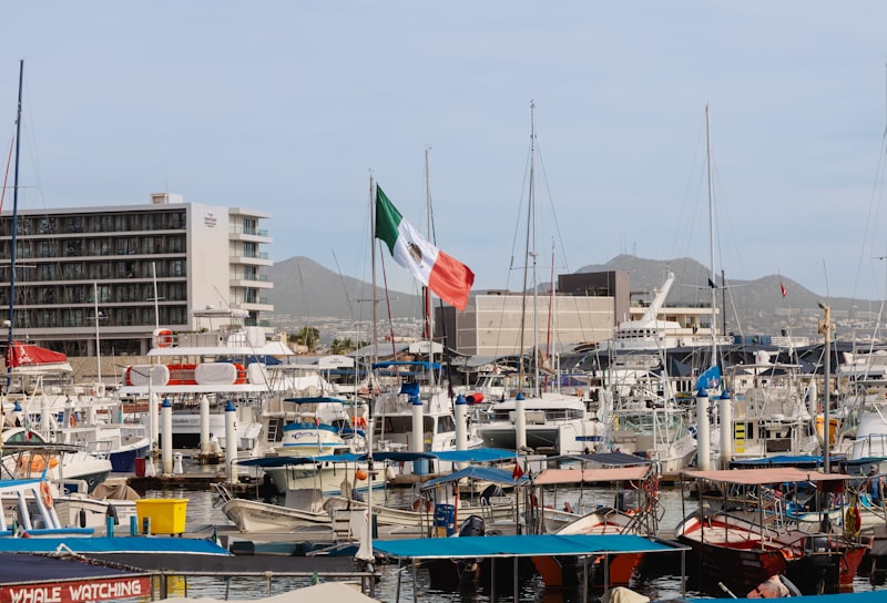 Mexican flag flies over a busy marina with many boats.